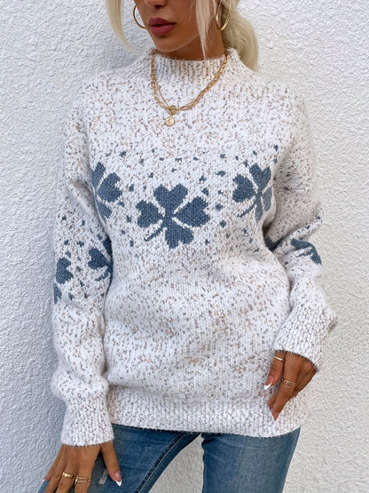 Frau in weißem Strickpullover mit blauen Blumenmuster, goldene Kette, lässiger Look.