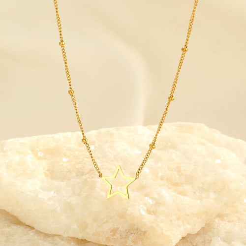 Goldene Stern-Halskette auf hellem Hintergrund, elegantes Schmuckdesign, modisches Accessoire.