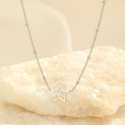 Silberne Stern-Halskette auf hellem Stein, eleganter Schmuck, minimalistisches Design.