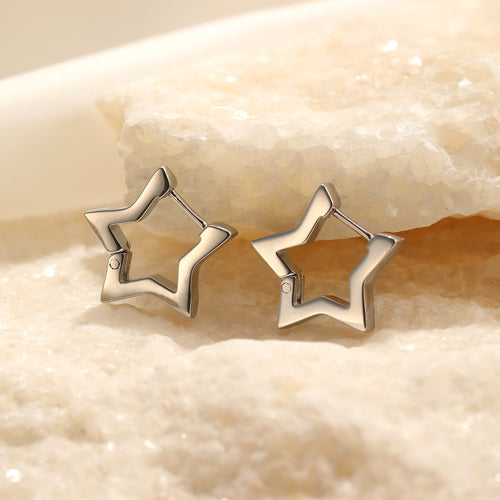 Sternförmige Ohrringe aus Silber auf sandfarbenem Hintergrund, modischer Schmuck.