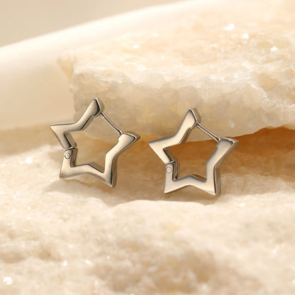 Sternförmige Ohrringe aus Silber auf sandfarbenem Hintergrund, modischer Schmuck.