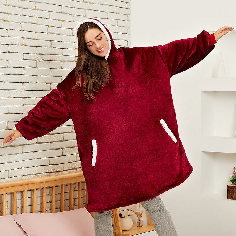 Frau in rotem, übergroßem Hoodie aus Fleece mit Kapuze und Taschen, gemütliche Winterbekleidung.