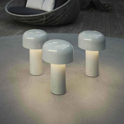 Drei weiße LED-Tischlampen im Freien auf grauem Tisch, modernes Design, stimmungsvolle Beleuchtung.