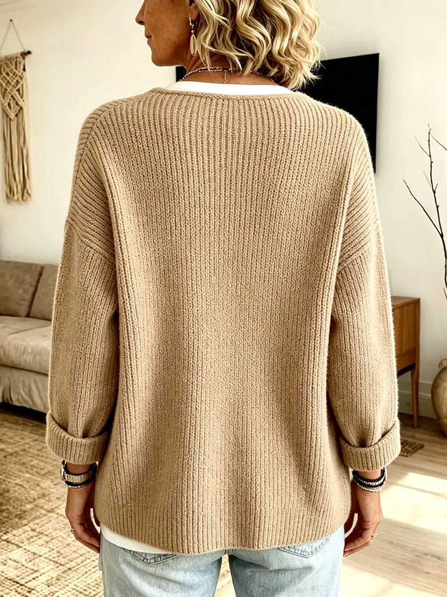 Baksidan av den beige ribbstickade koftan, med uppvikta ärmar, buren över vit topp och jeans 2