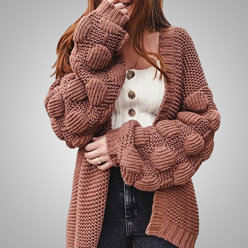 Frau trägt braunen Strickcardigan mit Zopfmuster, weiße Knopfleiste, modisch, gemütlich.