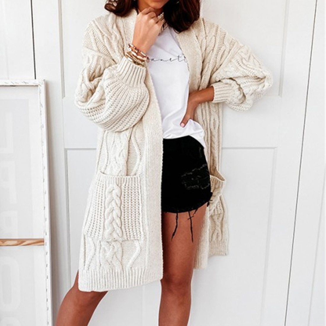 Frau trägt cremefarbenen Strick-Cardigan, lässig, mit Taschen, über weißem T-Shirt und Shorts.