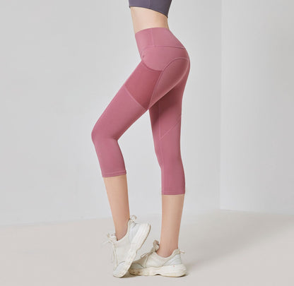 Frau in rosa Sportleggings und weißen Turnschuhen, seitlich stehend, vor neutralem Hintergrund.