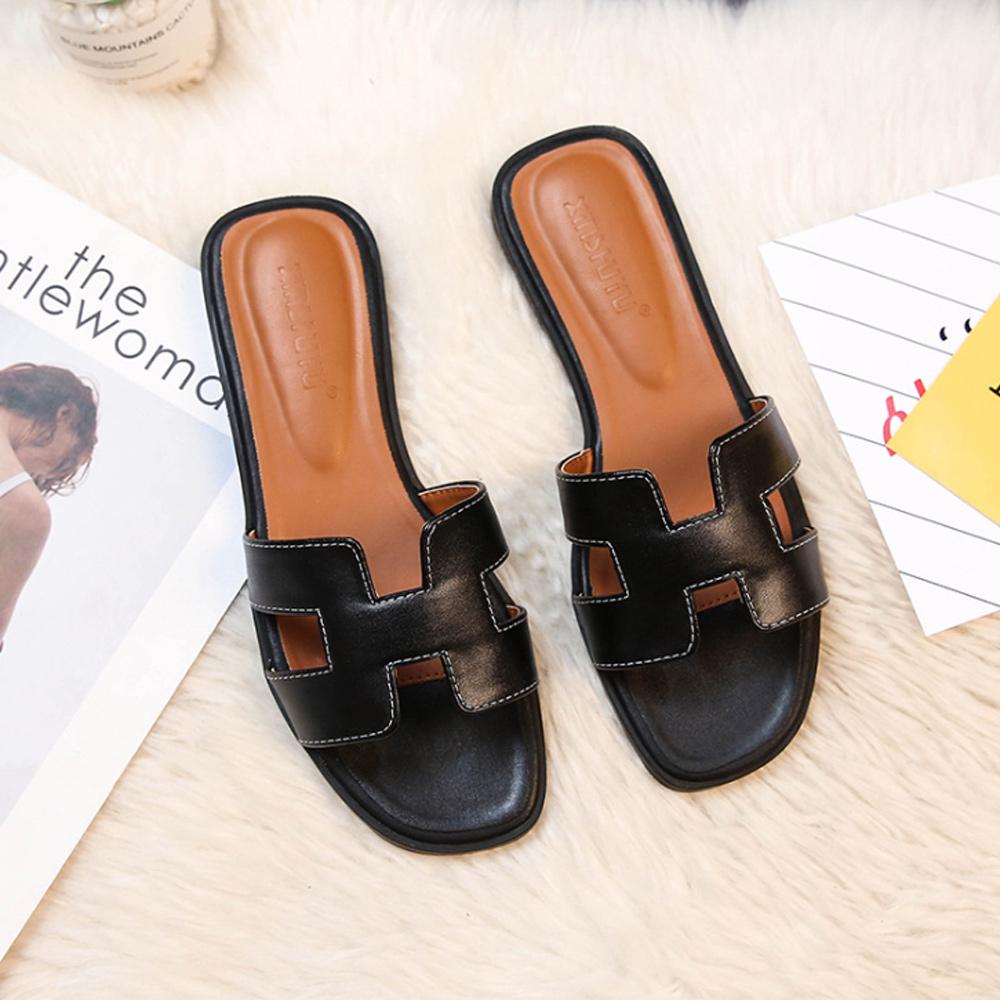 Schwarze Leder-Sandalen für Damen, flach, modisch, bequem, auf weißem Hintergrund.