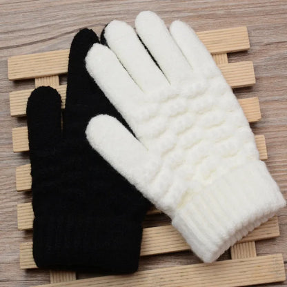 Schwarze und weiße Strickhandschuhe aus Wolle auf Holzunterlage, Wintermode Accessoire.