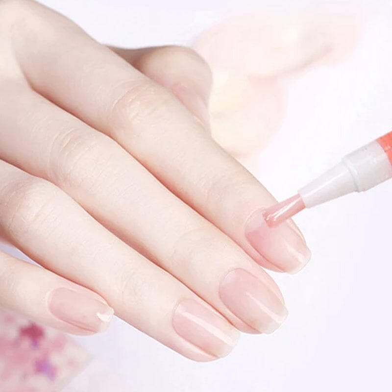 Närbild på hand med rosa naglar där penselspetsen stryker olja på nagelbandet 11