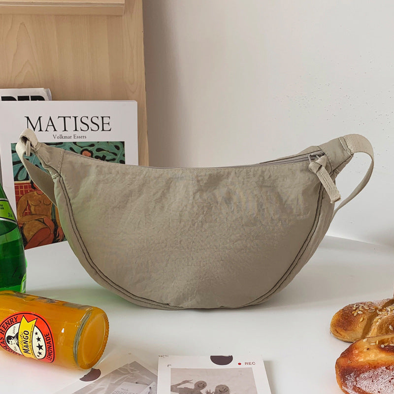 Beigefarbene Umhängetasche aus Stoff auf Tisch, modisch, praktisch, ideal für den Alltag.