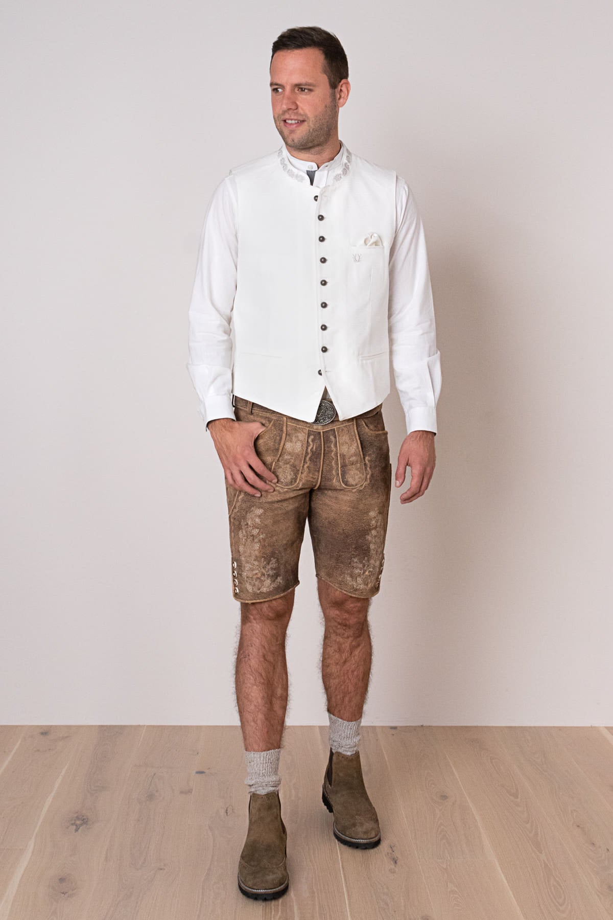 Mann in traditioneller Lederhose und weißer Weste, bayerische Tracht, Trachtenmode Herren.