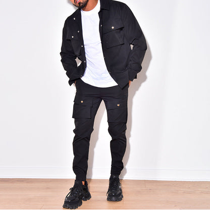 Mann in schwarzer Cargo-Jacke und Hose, weißes T-Shirt, schwarze Sneaker, modisch, urban.