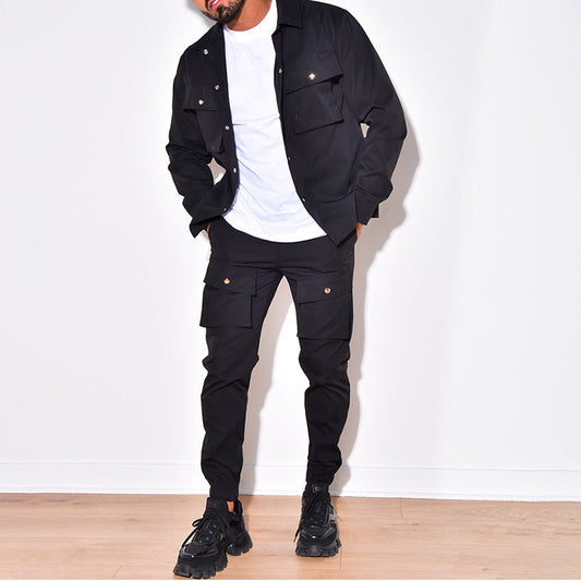 Mann in schwarzer Cargo-Jacke und Hose, weißes T-Shirt, schwarze Sneaker, modisch, urban.