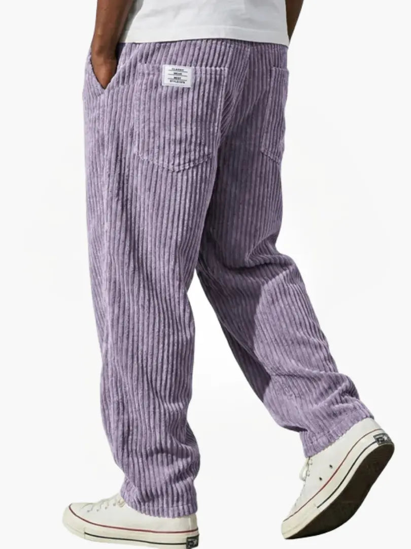 Lila manchesterbyxa bakifrån på gående modell med vit t-shirt, bakficka, liten etikett och vita sneakers. 9