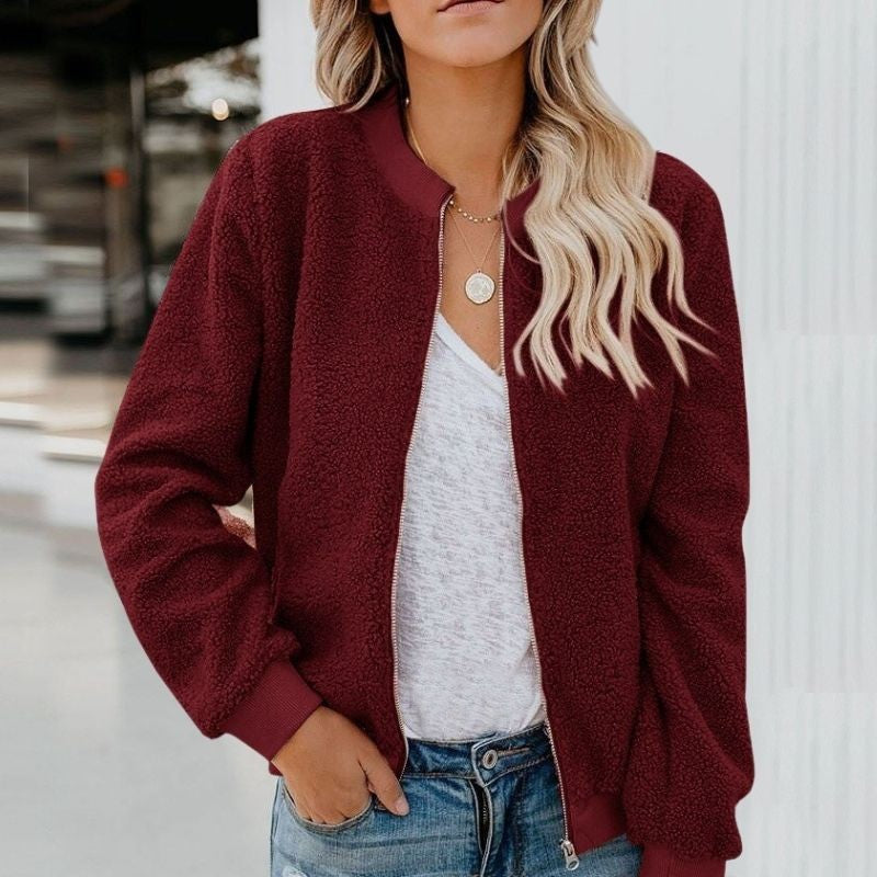 Frau trägt bordeauxrote Teddyjacke, weißes T-Shirt, Jeans; modische Damenbekleidung.