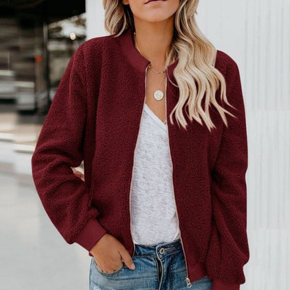 Frau trägt bordeauxrote Teddyjacke, weißes T-Shirt, Jeans; modische Damenbekleidung.