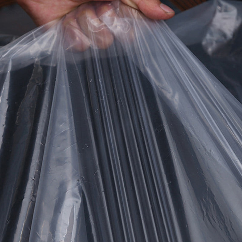 Hand håller upp en bit av den tunna, klara plastduken så att veck och genomskinlighet syns. 6