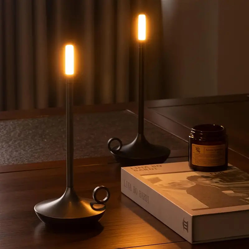 Moderne schwarze LED-Kerzenleuchte auf Holztisch, stimmungsvolle Beleuchtung, Inneneinrichtung.