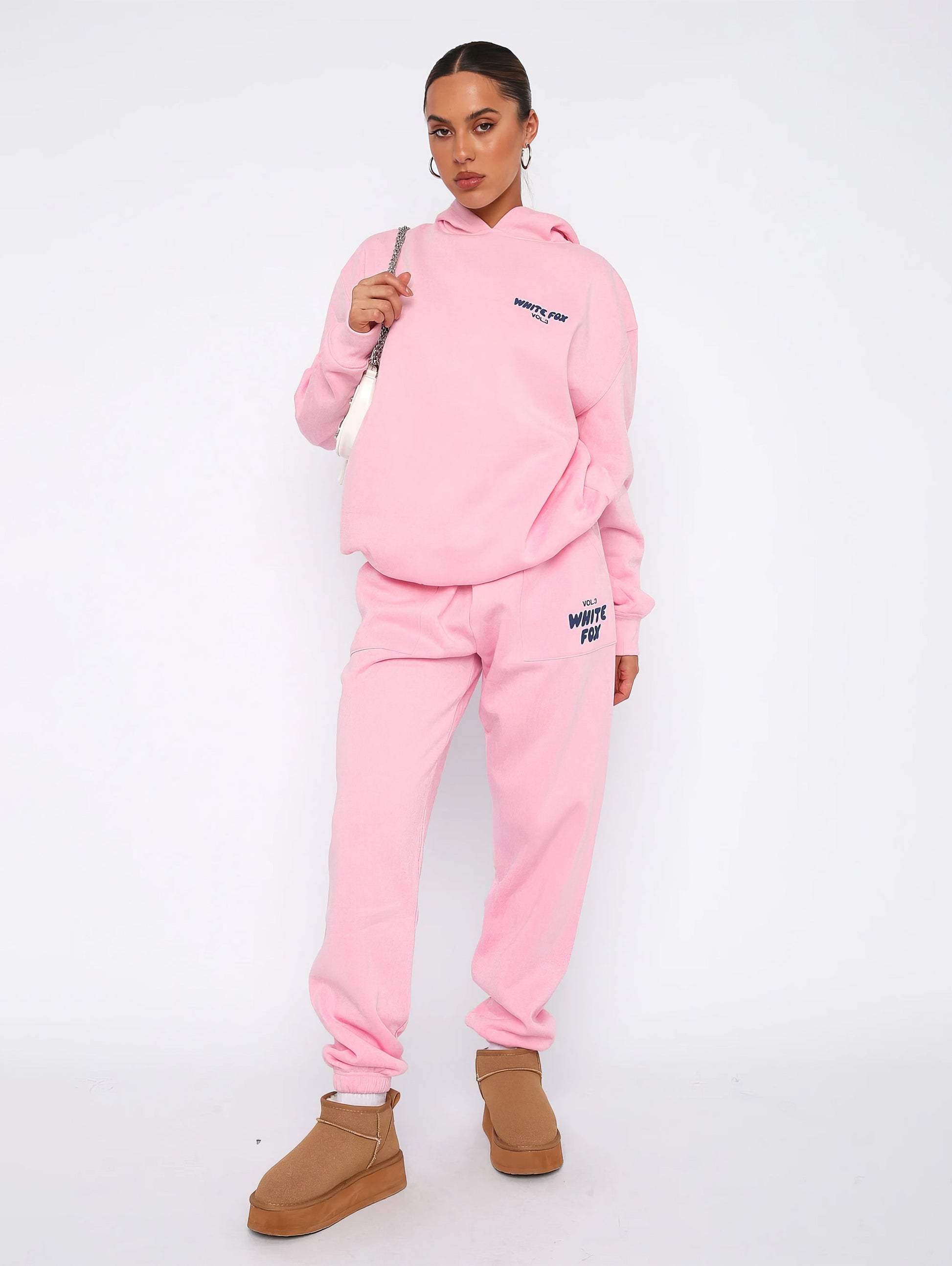 Frau in rosa Hoodie und Jogginghose, braune Stiefel, lässige Mode, Winteroutfit.