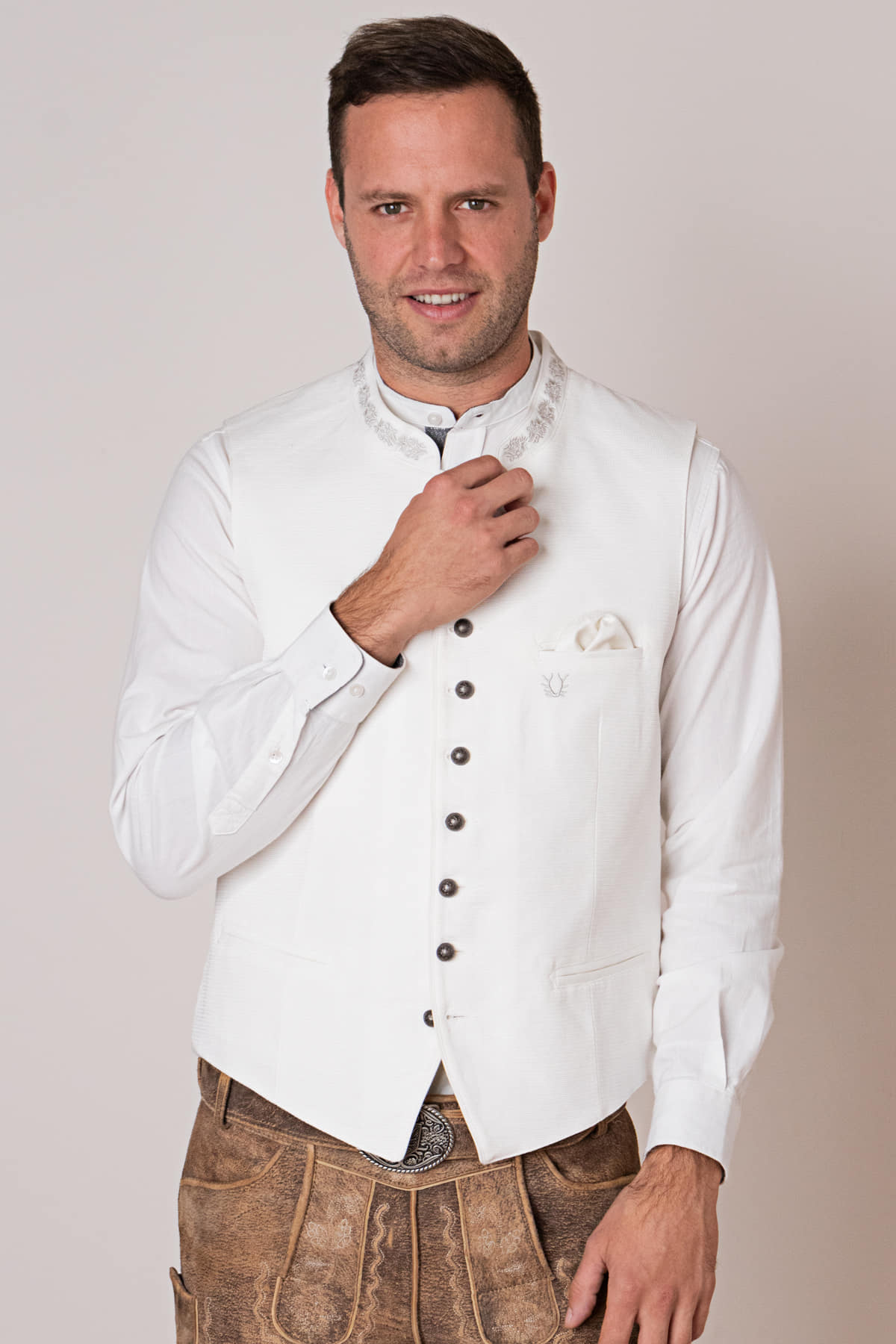 Mann in weißer Trachtenweste und Lederhose, traditionelles bayerisches Outfit.