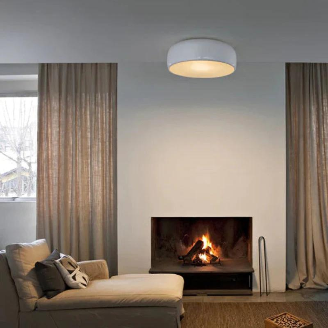 Moderne Wohnzimmerbeleuchtung, runde Deckenleuchte, weiß, über Kamin, gemütliches Ambiente.