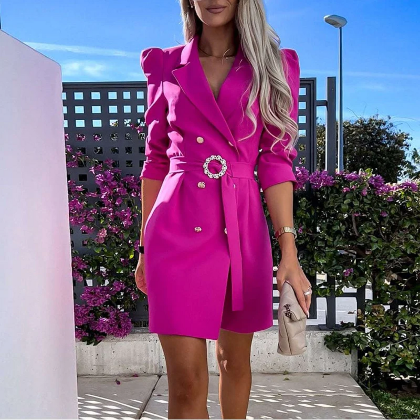 Frau in pinkem Blazer-Kleid mit Gürtel, elegantes Outfit, Sommermode, draußen, Blumenhintergrund.