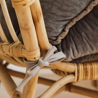 Rattan-Stuhl mit grauem Kissen, Nahaufnahme, handgefertigt, skandinavisches Design.