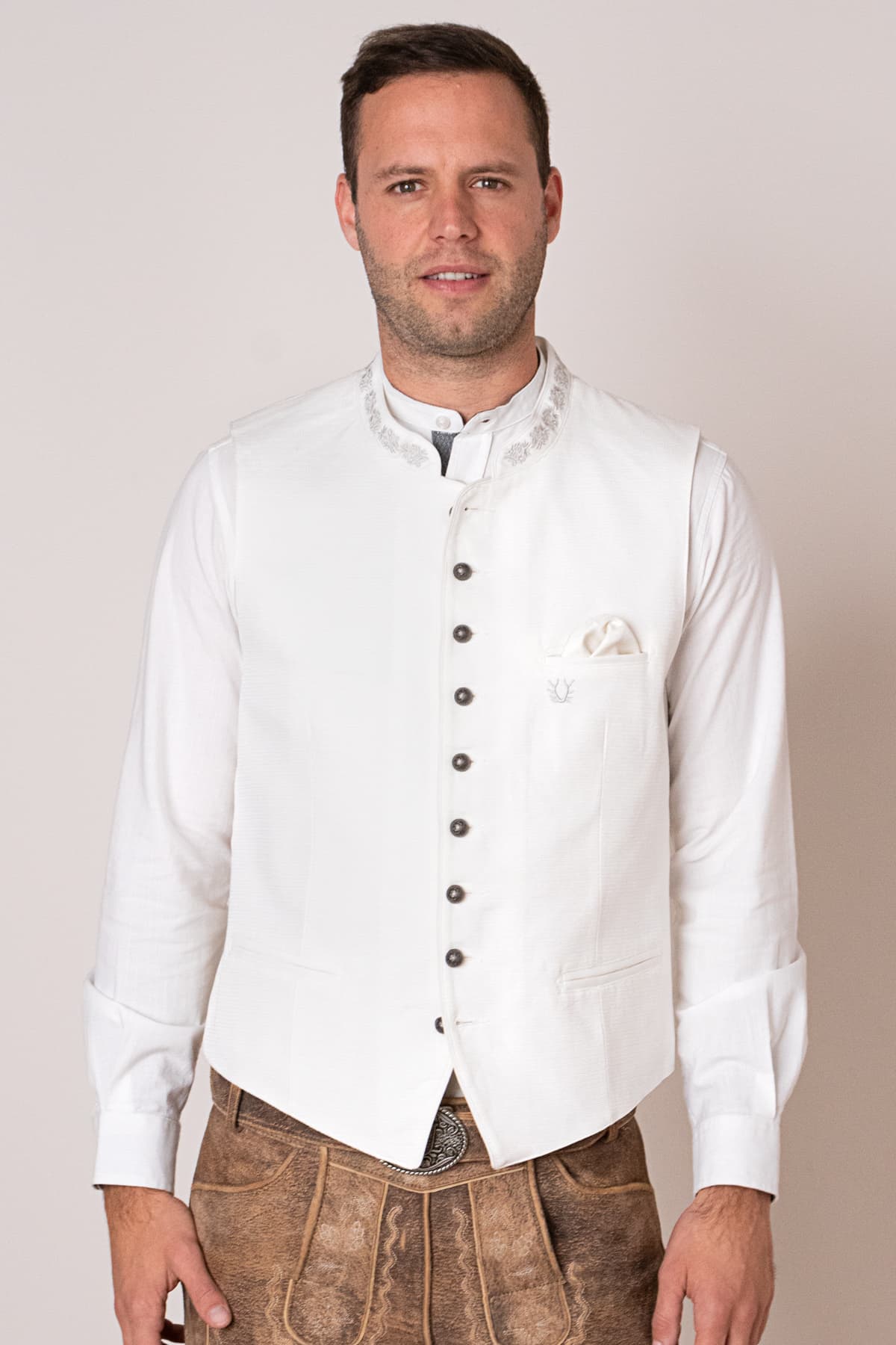 Mann in weißer Trachtenweste und Lederhose, traditionelles bayerisches Outfit.