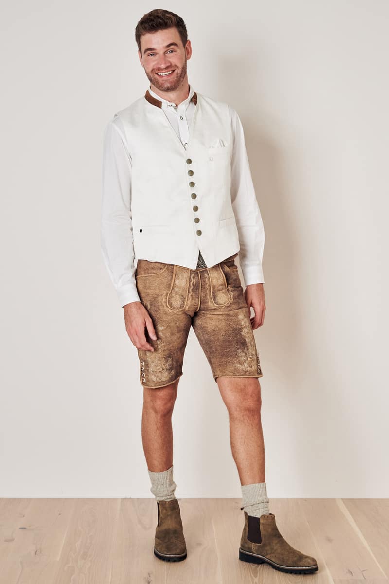 Mann in weißer Weste und brauner Lederhose, traditionelles bayerisches Outfit, Trachtenmode.