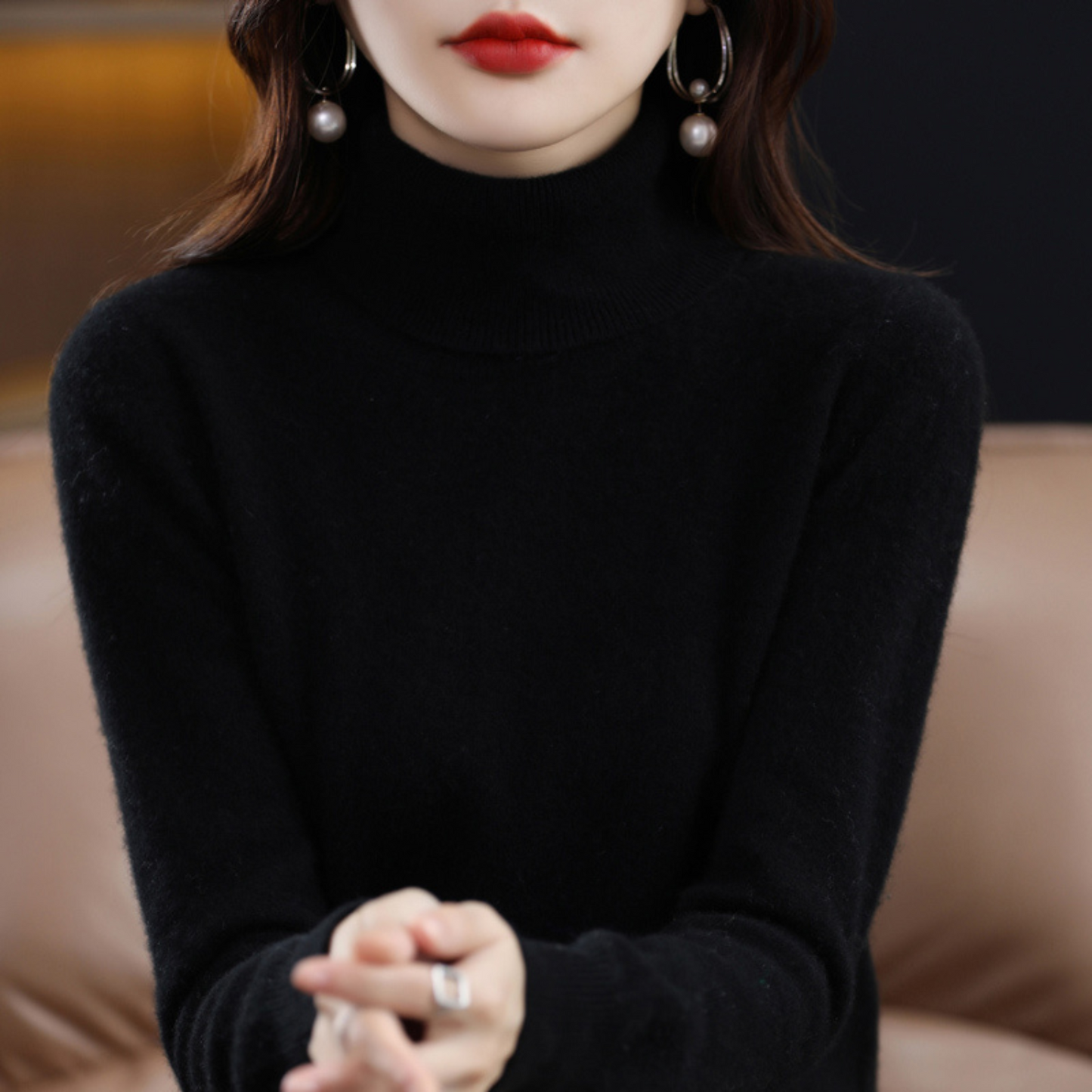 Frau in schwarzem Rollkragenpullover, elegante Ohrringe, roter Lippenstift, stilvolle Mode.