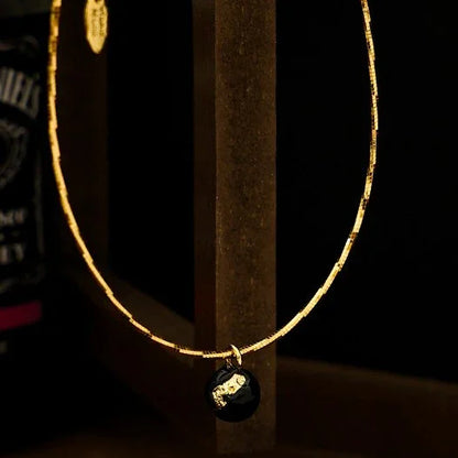 Goldene Halskette mit schwarzem Anhänger, elegantes Schmuckdesign, luxuriöses Accessoire.