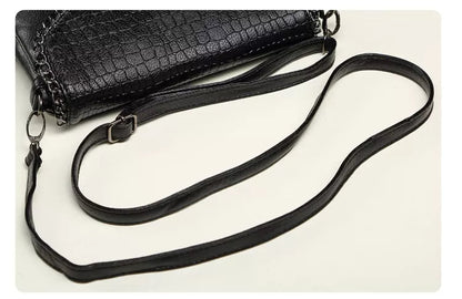 Schwarze Lederhandtasche mit Krokodilprägung und verstellbarem Schulterriemen.