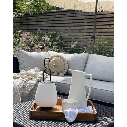 Weiße LED-Laterne und Kanne auf Holztablett, Gartenmöbel, Outdoor-Dekoration, Sommer.