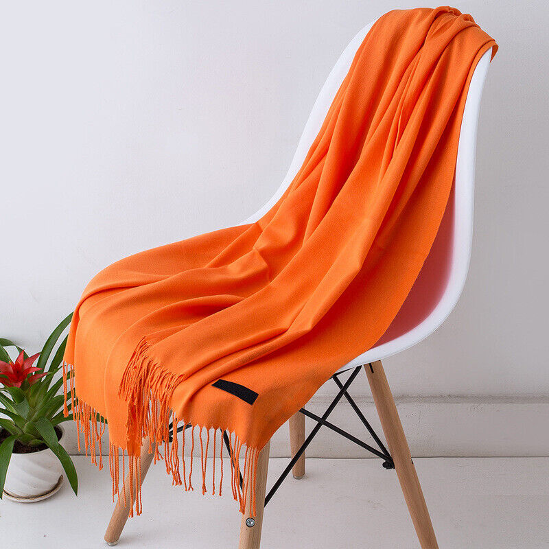 Orangefarbener Schal aus Kaschmir auf weißem Stuhl, weiches Material, modisches Accessoire.