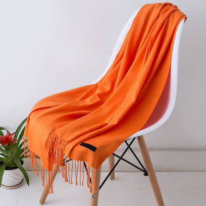 Orangefarbener Schal aus Kaschmir auf weißem Stuhl, weiches Material, modisches Accessoire.