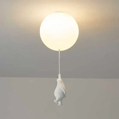 Weiße Deckenleuchte mit rundem Lampenschirm und hängender Pinguinfigur, modernes Design.