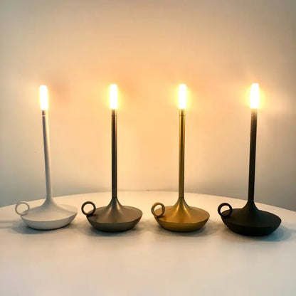 Vier moderne LED-Kerzenleuchter in Weiß, Grau, Gold und Schwarz auf einem Tisch.