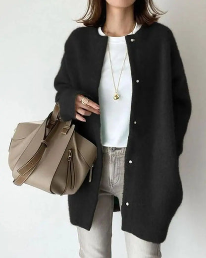 Frau mit schwarzem Cardigan, weißem T-Shirt, beiger Handtasche, modisch, lässiger Look.
