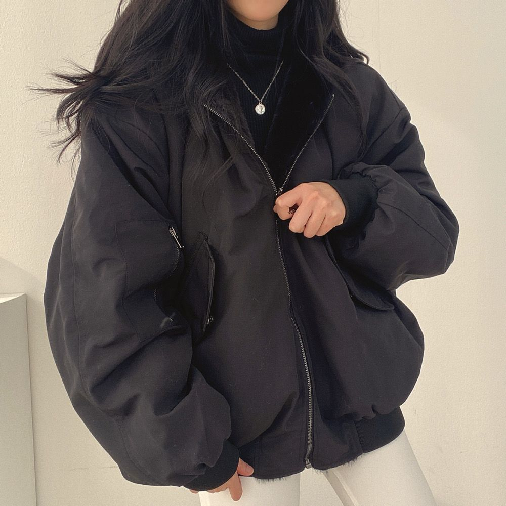 Frau in schwarzer Oversize-Jacke, Reißverschluss, Wintermode, lässiger Stil, Damenbekleidung.