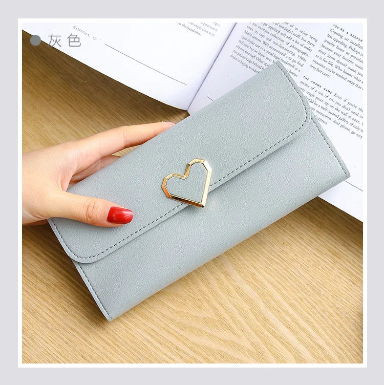 Graues Damenportemonnaie aus Leder mit Herzverschluss, elegante Geldbörse auf Holztisch.