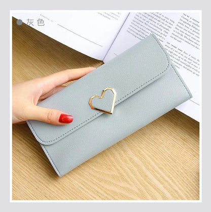 Graues Damenportemonnaie aus Leder mit Herzverschluss, elegante Geldbörse auf Holztisch.