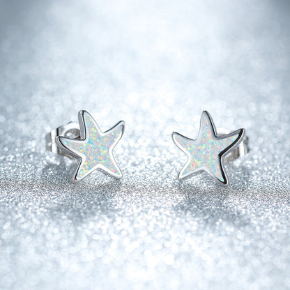 Silberne Stern-Ohrringe mit schimmerndem Opal-Design auf glitzerndem Hintergrund.