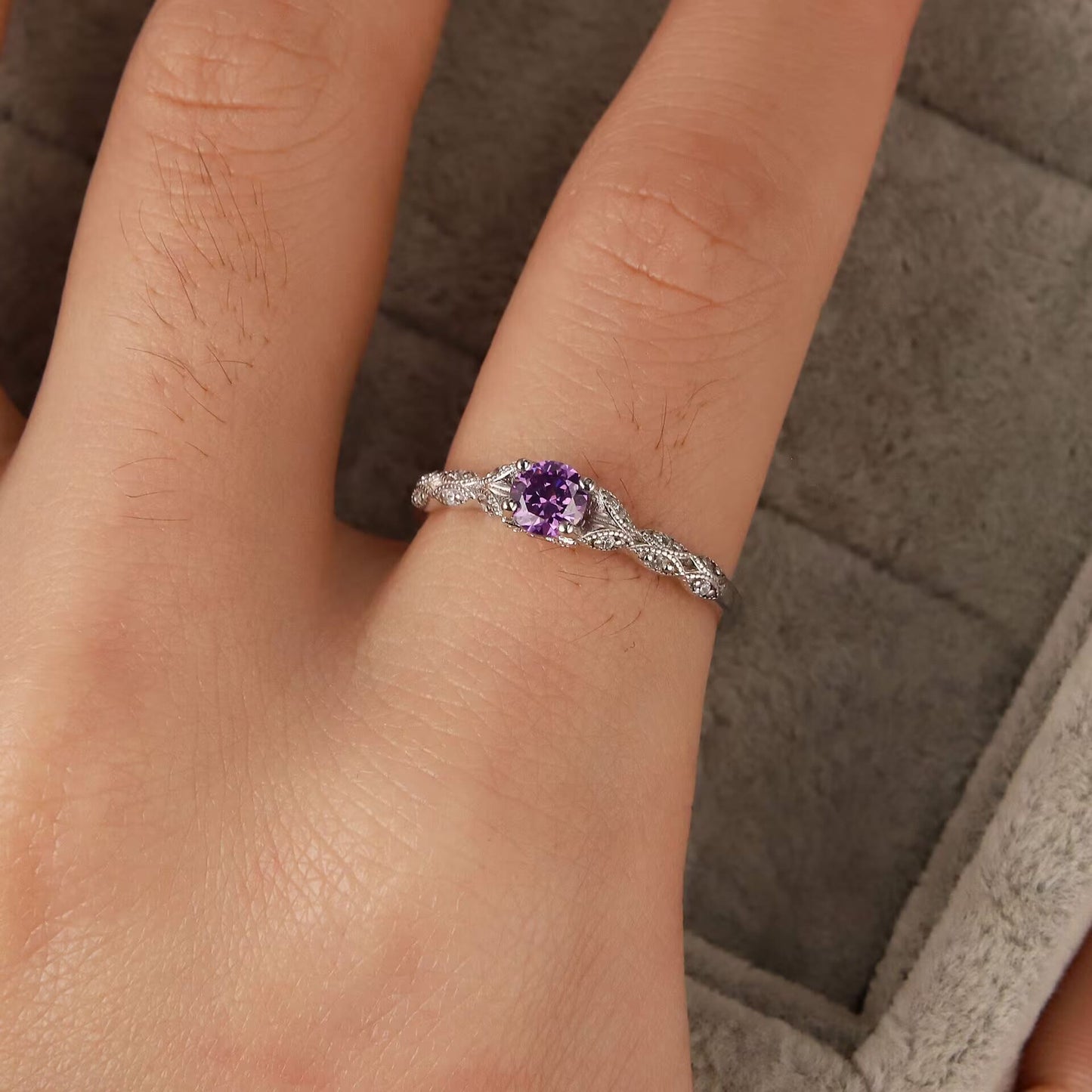 Silberner Verlobungsring mit lila Edelstein auf Finger, filigranes Design, Schmuck für Damen.