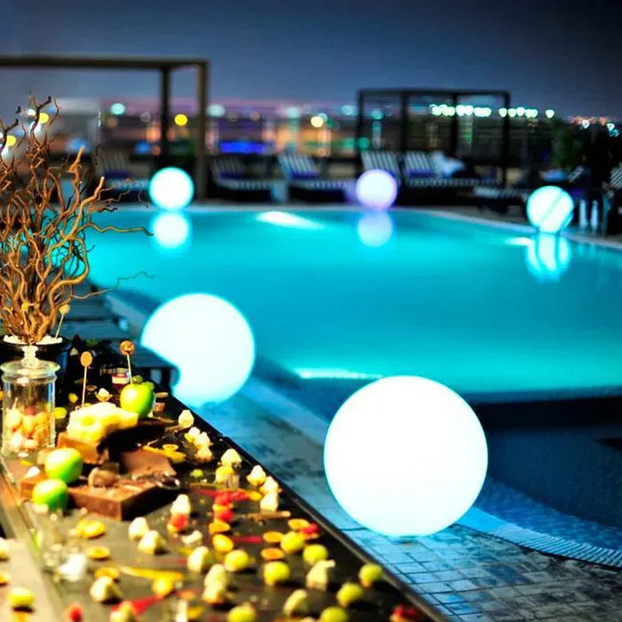 Luxuriöser Hotelpool bei Nacht mit leuchtenden Kugeln und elegantem Buffet im Vordergrund.