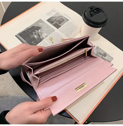 Rosa Damen-Geldbörse aus Leder, geöffnet auf Tisch mit Kaffeetasse, elegantes Design, viele Fächer.