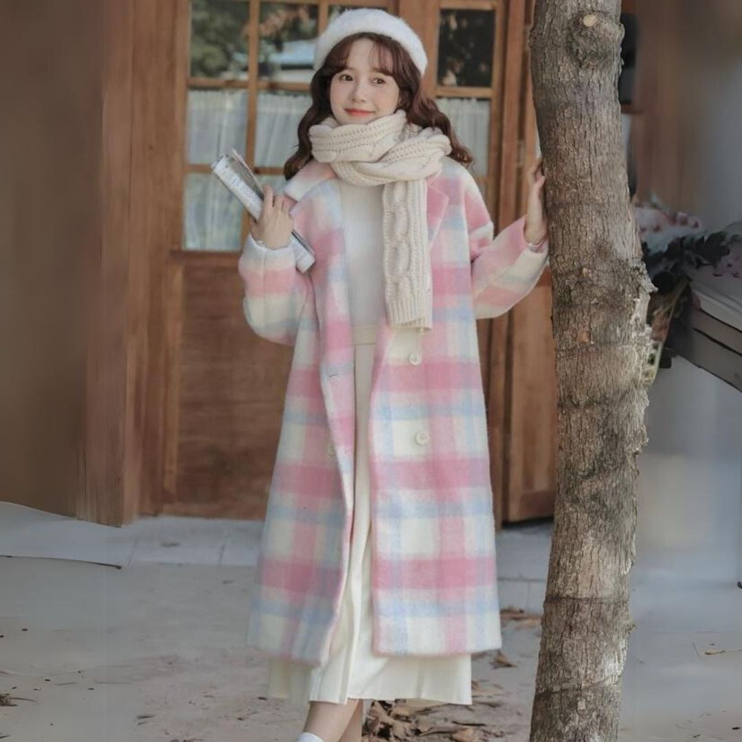 Frau im karierten Mantel, rosa-weiß, mit Schal und Mütze, steht draußen, Wintermode.