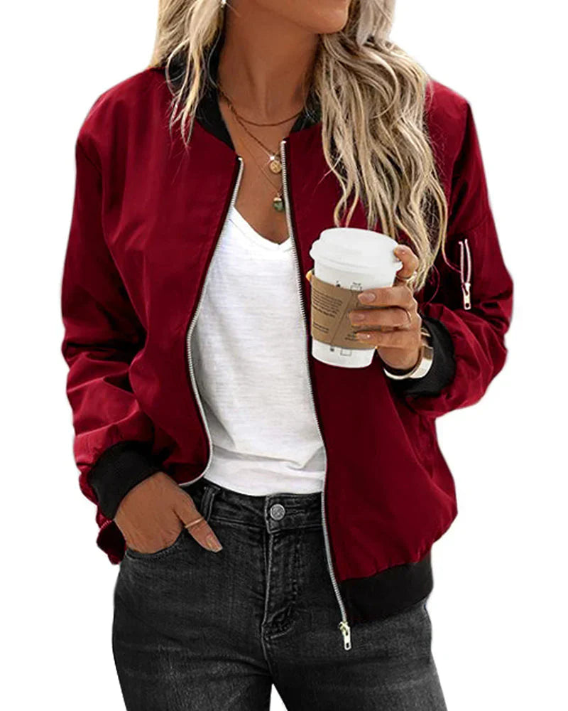 Frau in roter Bomberjacke, weißem T-Shirt, hält Kaffeebecher, lässiger Streetstyle-Look.
