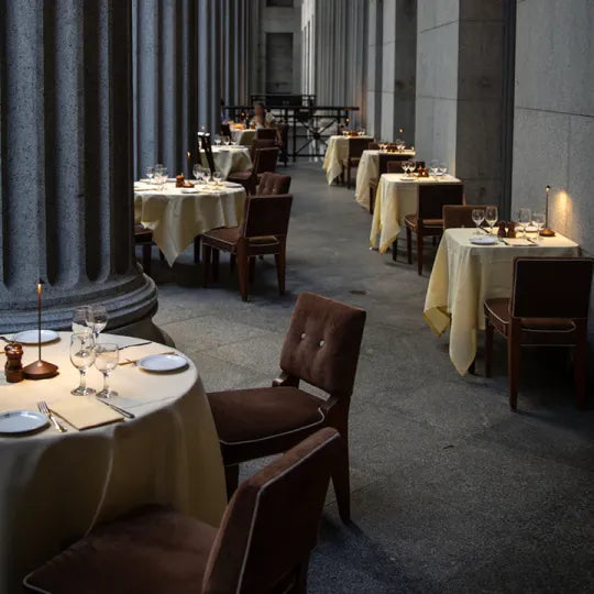 Elegantes Restaurant mit gedeckten Tischen, braunen Stühlen und Kerzenlicht, ideal für Abendessen.