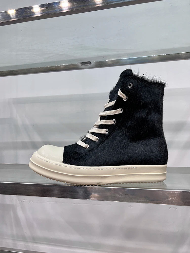 Schwarzer High-Top-Sneaker aus Leder mit weißer Sohle und Schnürsenkeln auf Metallregal.